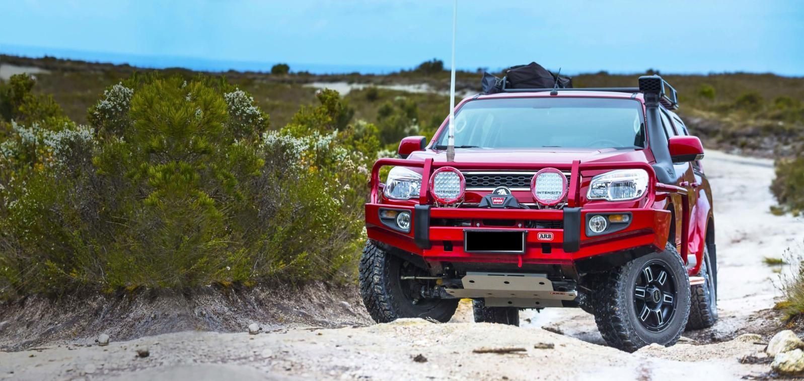 A Red Truck Is Driving Down A Dirt Road — Tech Tune Automotive and 4x4 ARB In Tully, QLD