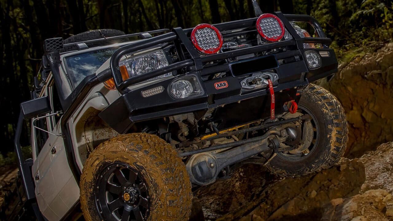 A Jeep Is Driving Down A Dirt Road In The Woods — Tech Tune Automotive and 4x4 ARB In Innisfail, QLD