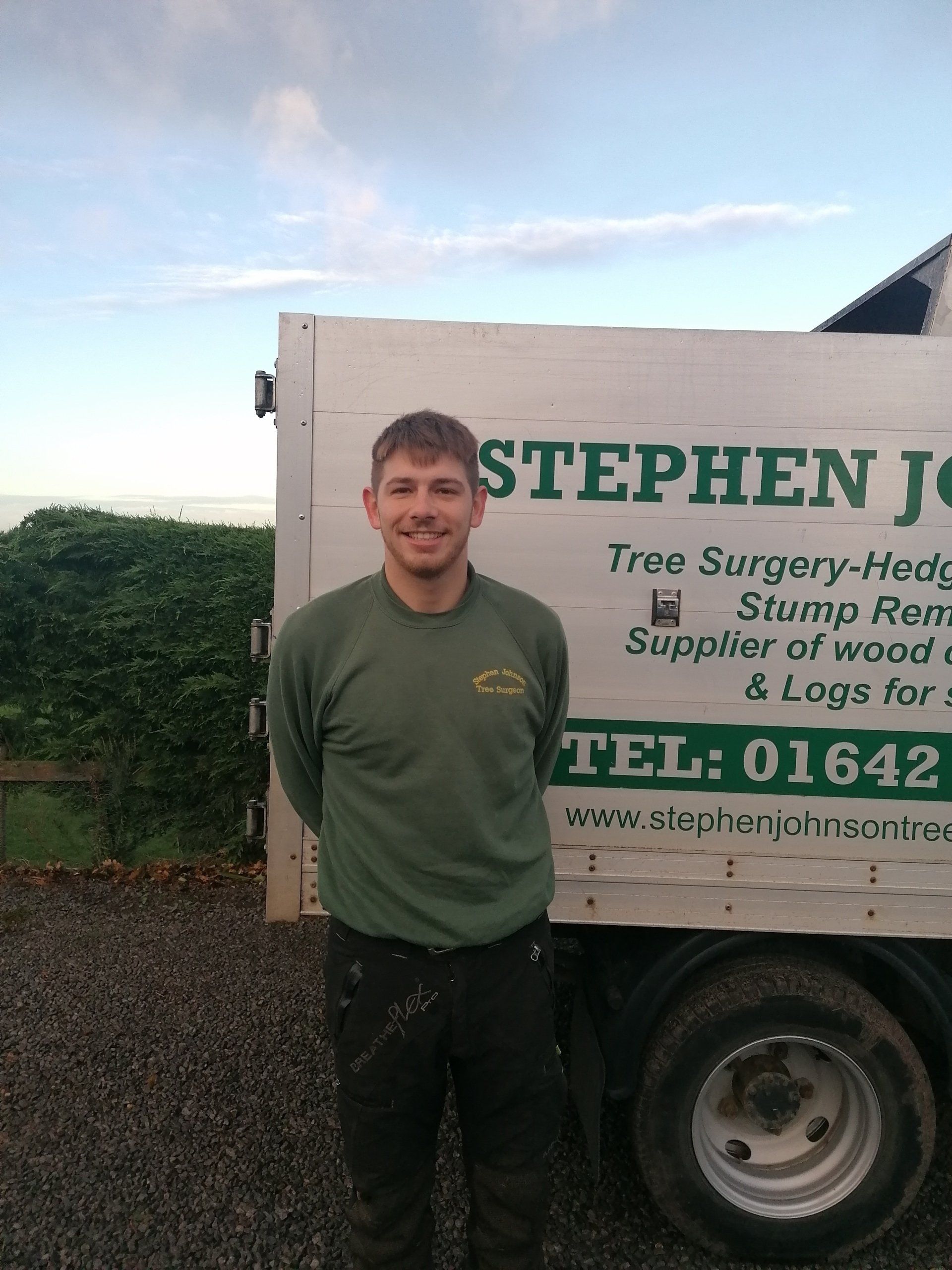 A man in a green shirt is standing in front of a stephen john truck