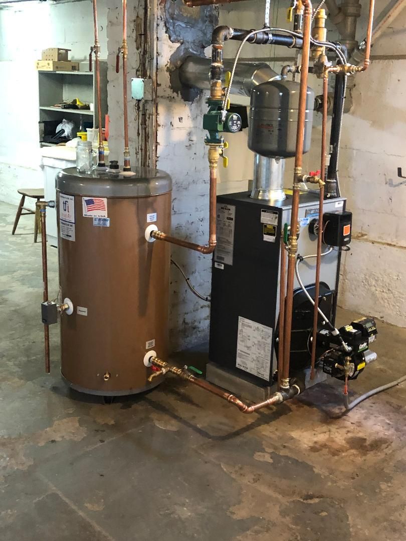 Water heater and boiler system with copper pipes in a basement.