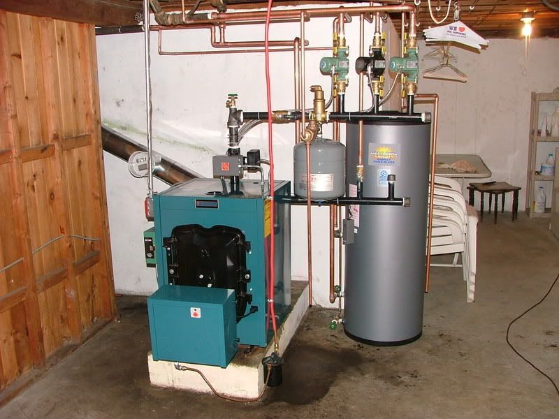 A basement with a teal boiler, copper pipes, and a water heater.