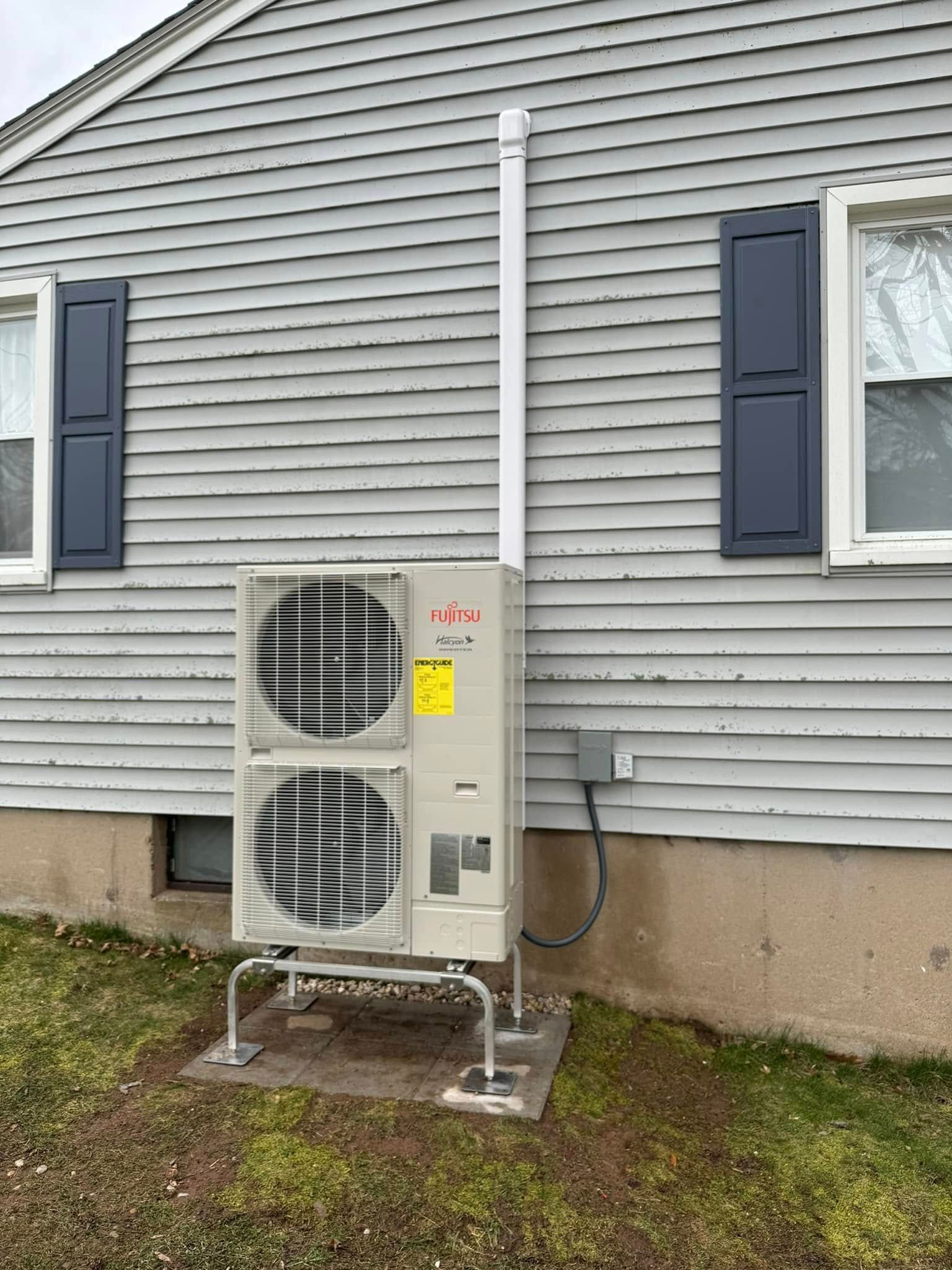 A large air conditioner is installed on the side of a house.