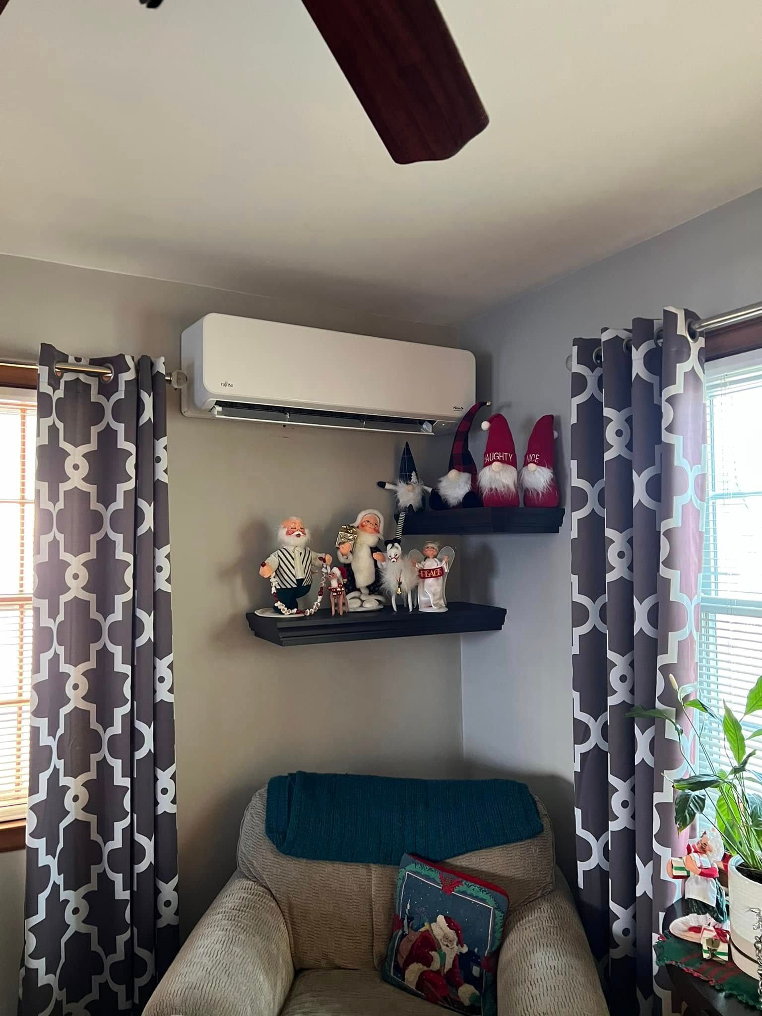 A living room with a chair , shelves , and a ceiling fan.
