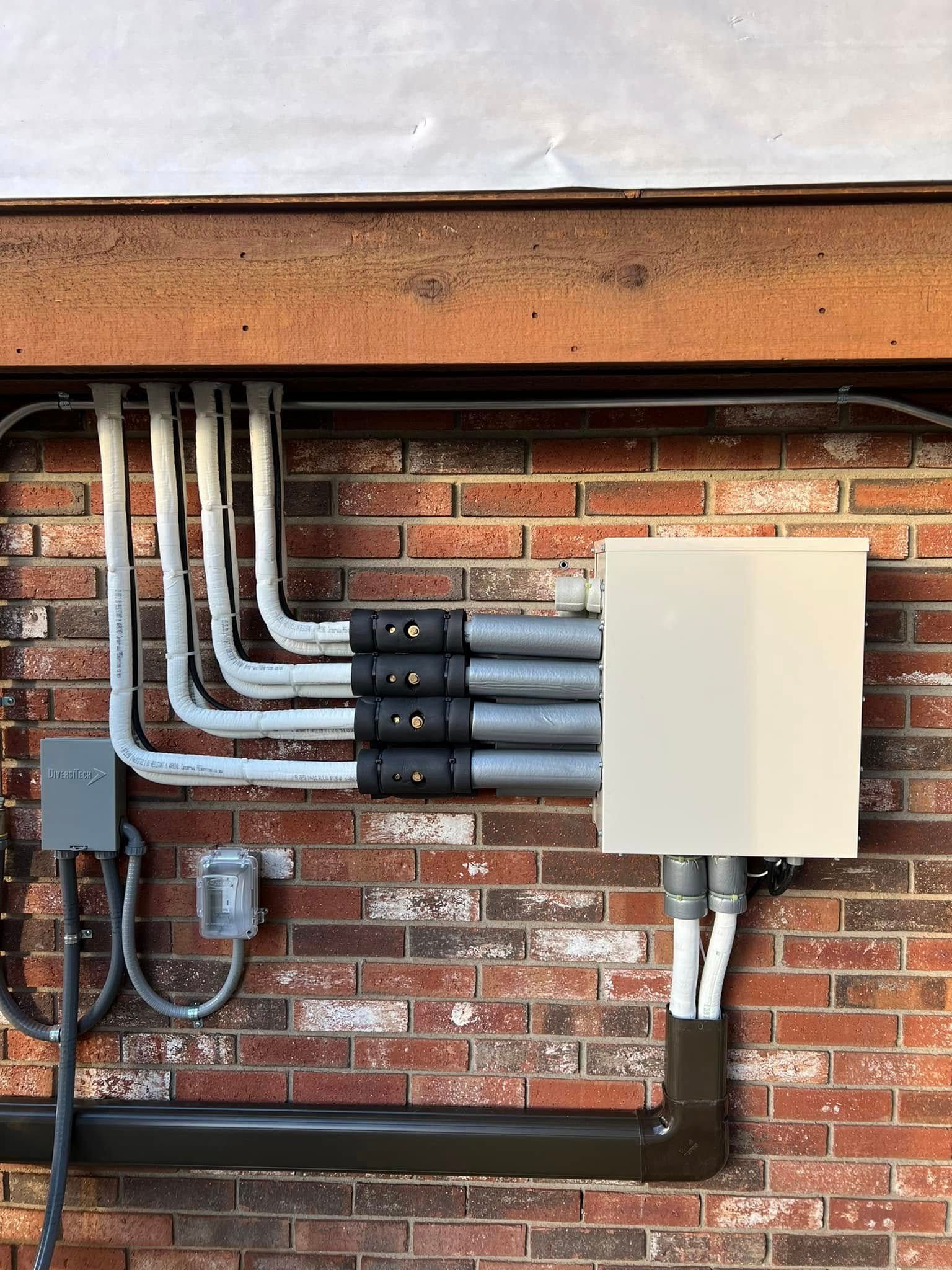 A brick wall with electrical wires and a box on it.