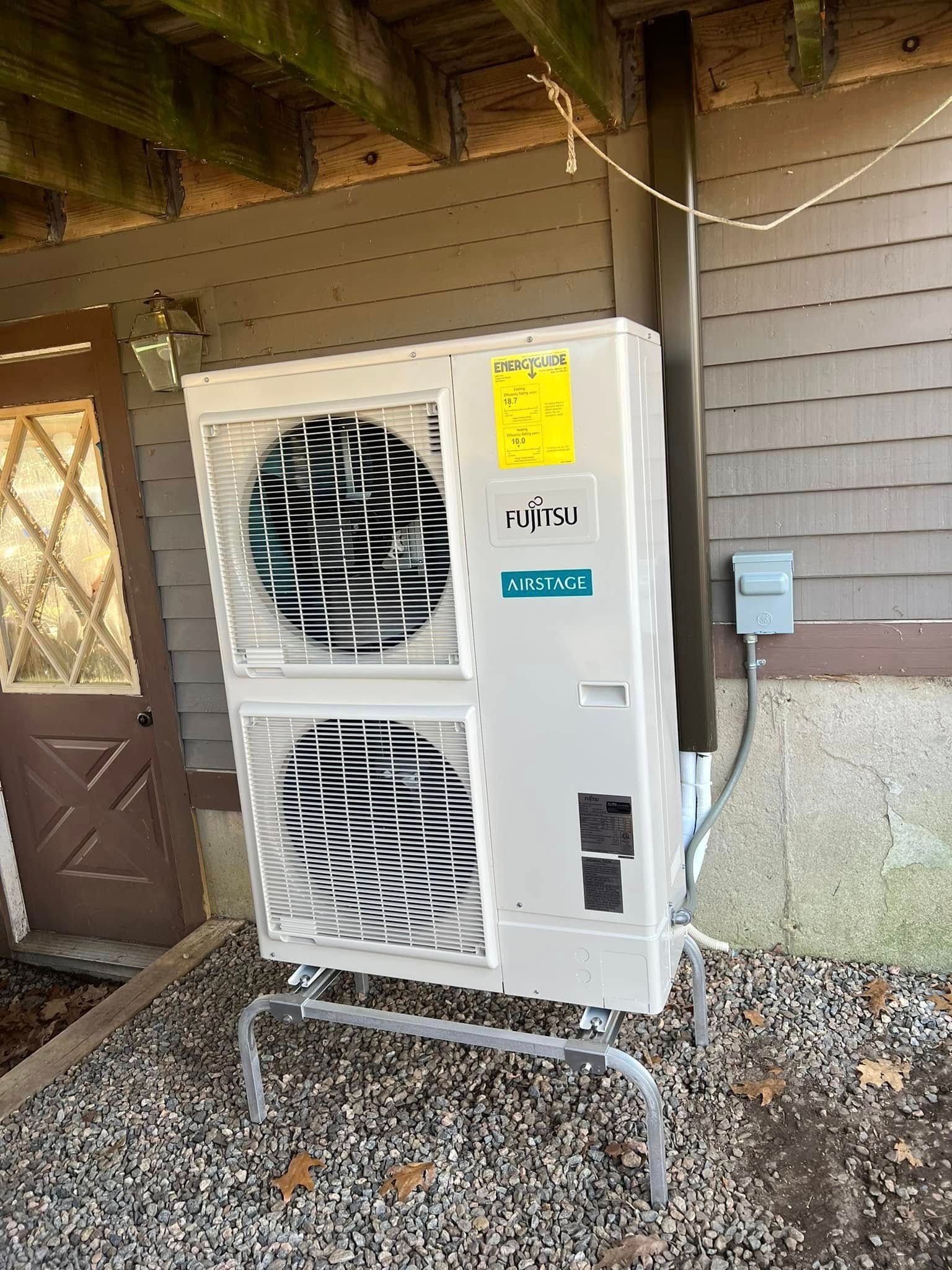 A large air conditioner is sitting outside of a house.