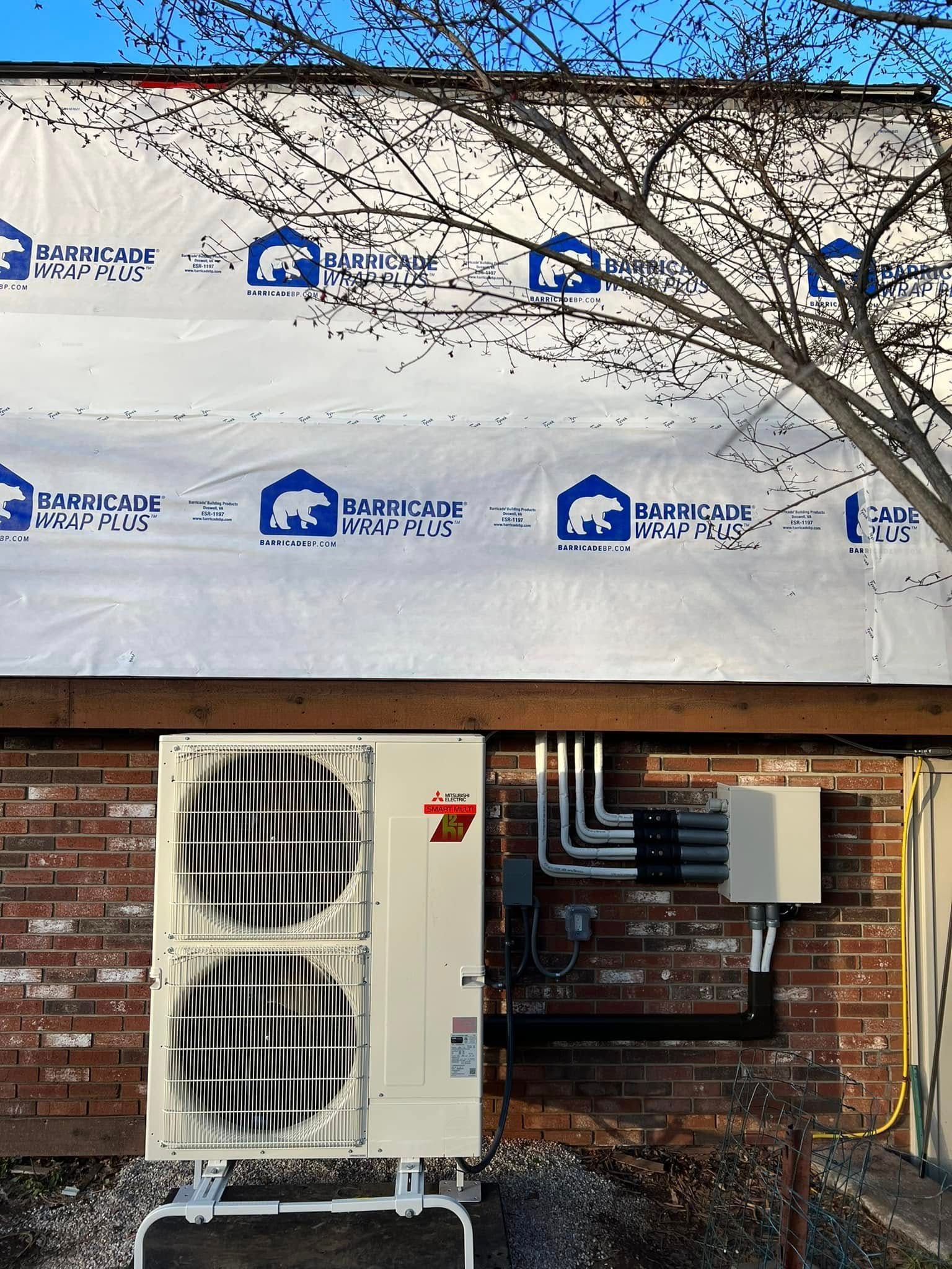 A white air conditioner is sitting on the side of a brick building.