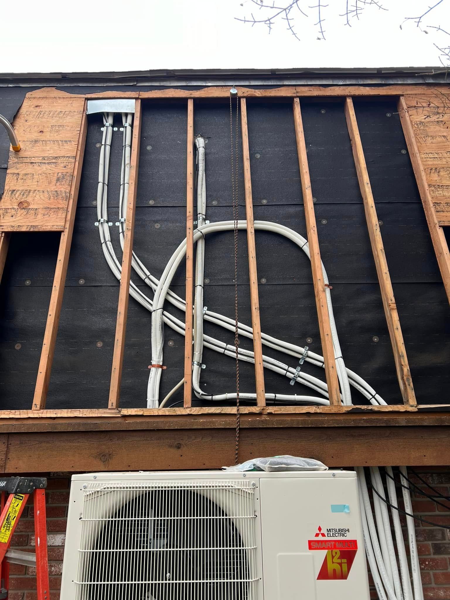 A mitsubishi air conditioner is being installed on the side of a building