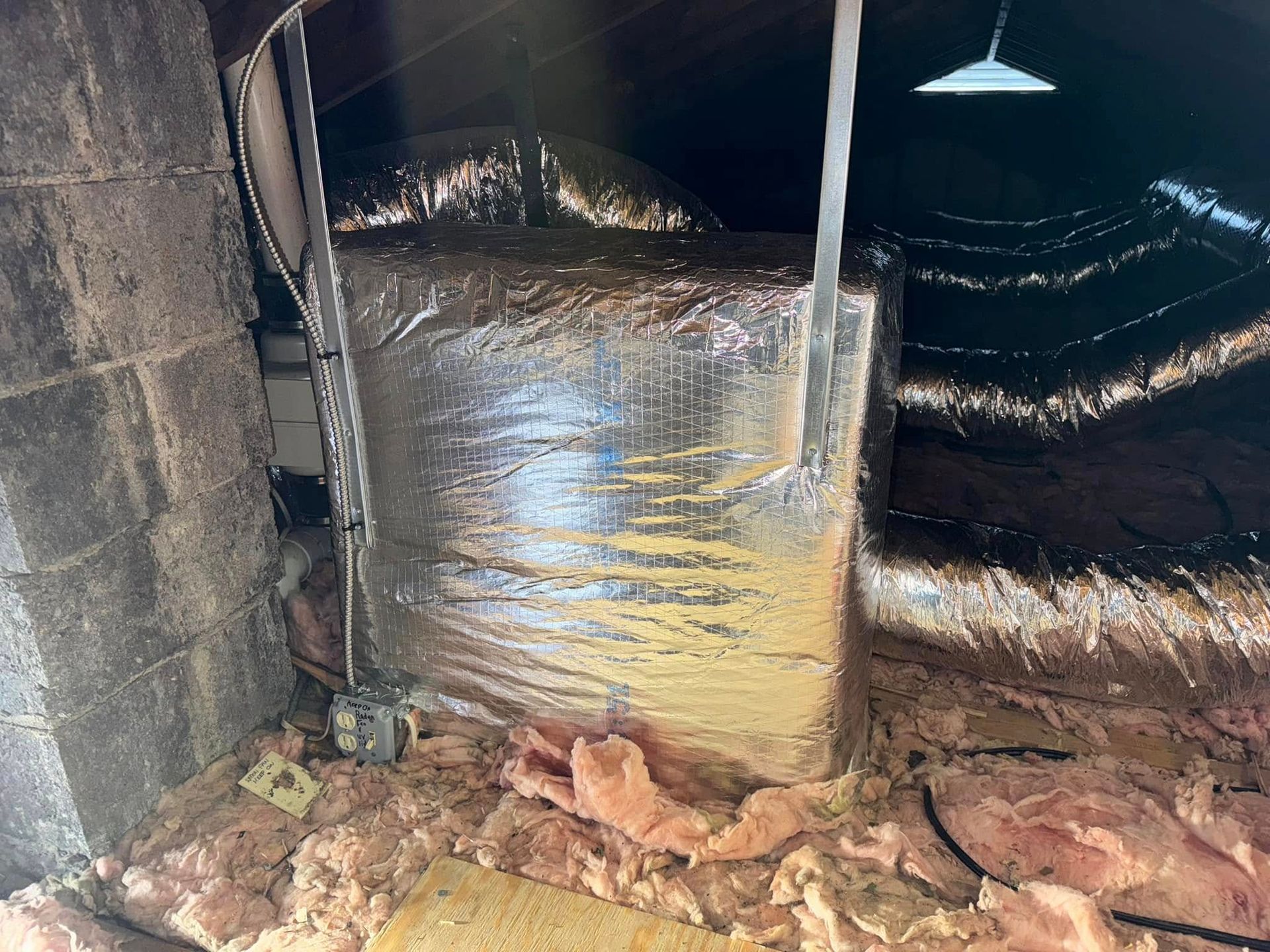 A large bag of insulation is sitting in the attic of a house.