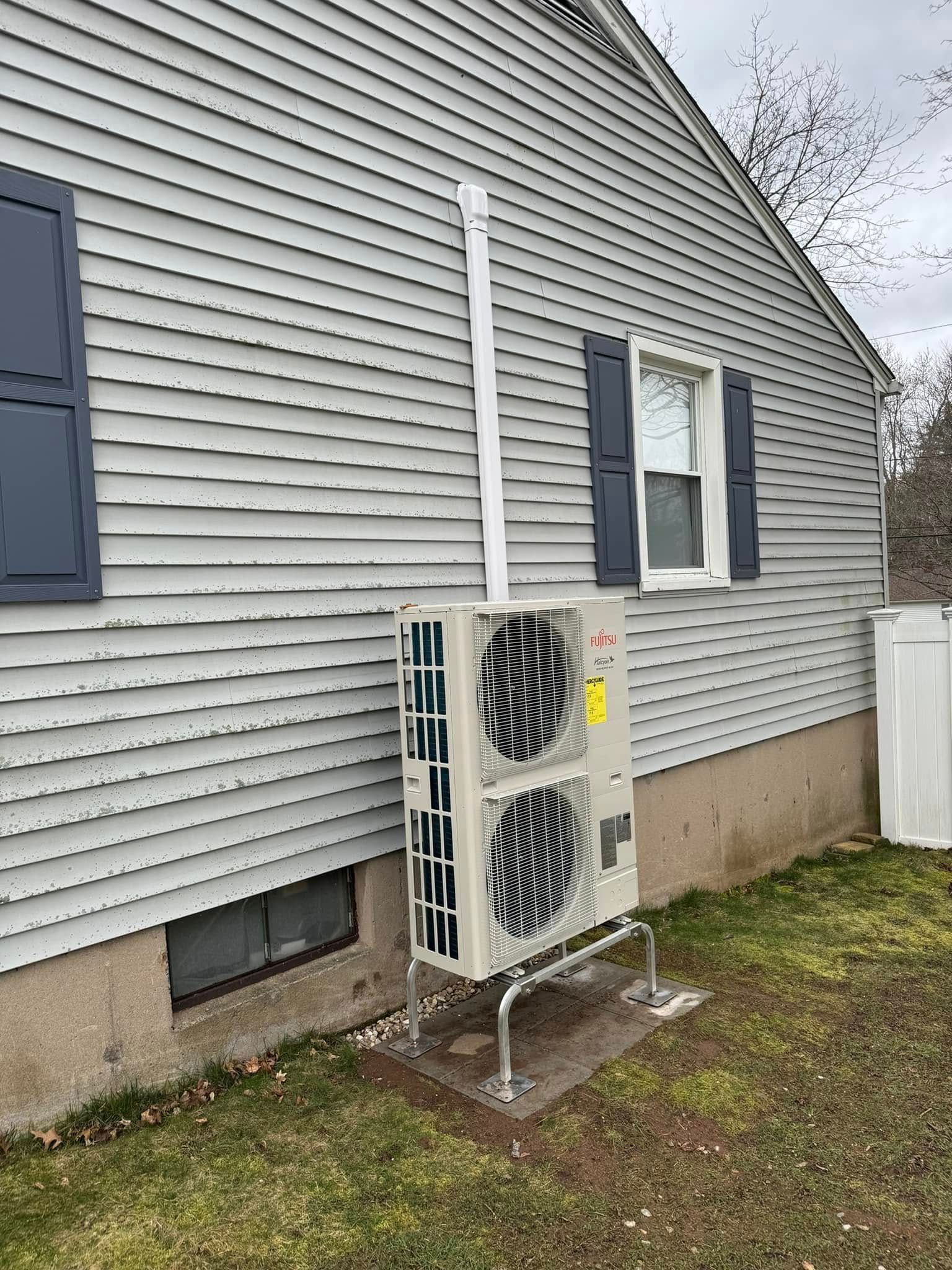 A large air conditioner is installed on the side of a house.