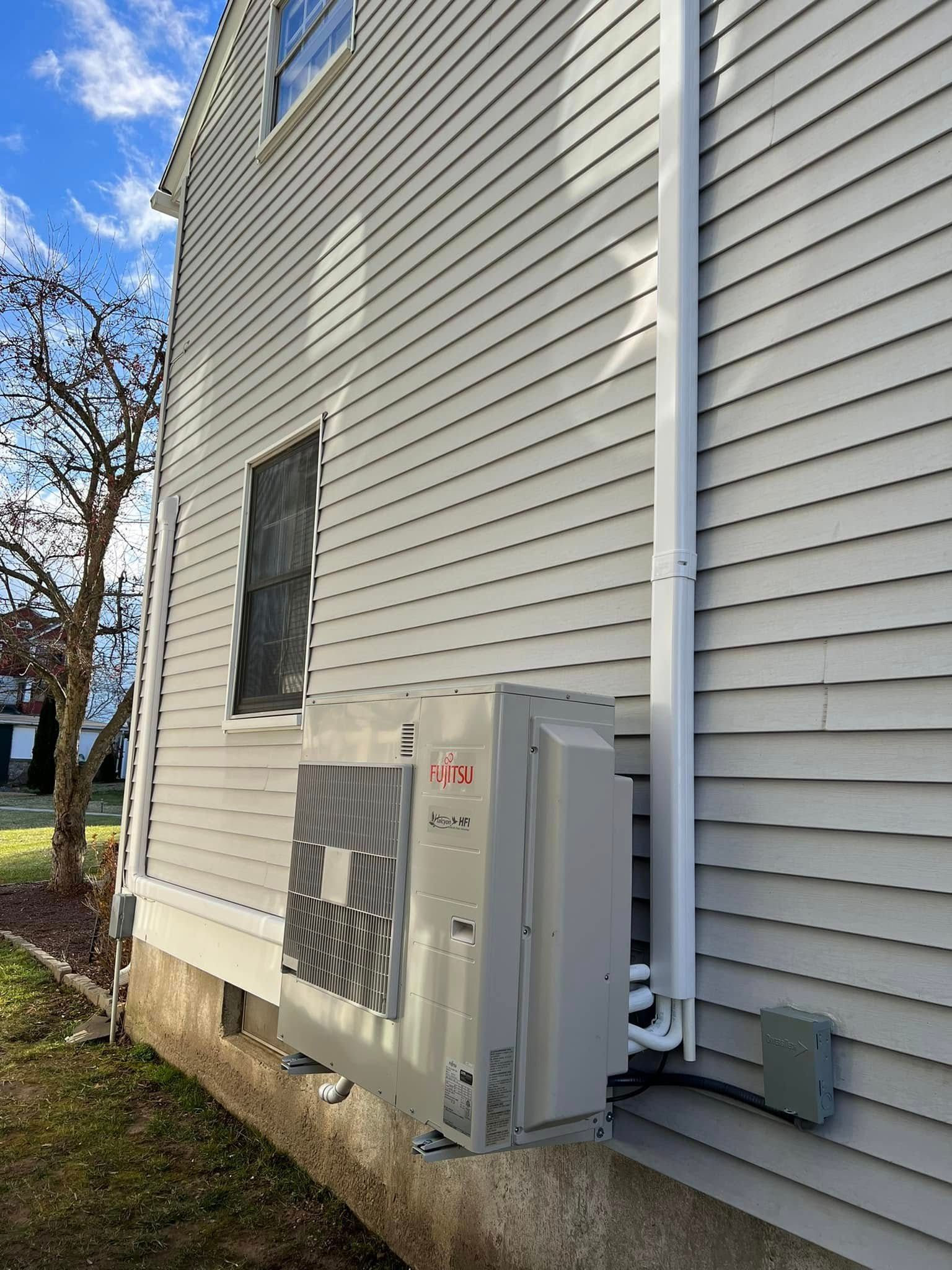 A large air conditioner is installed on the side of a house.