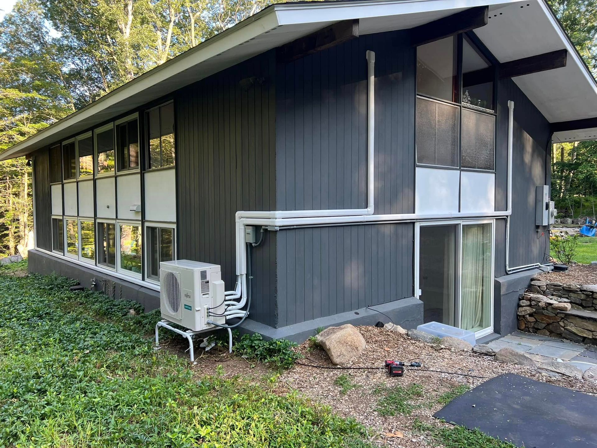 A house with a lot of windows and a small air conditioner on the side of it.