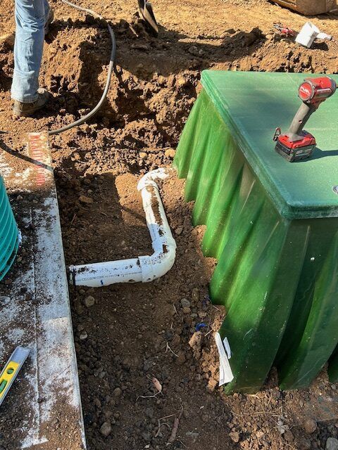 A person is working on a green box in the dirt.