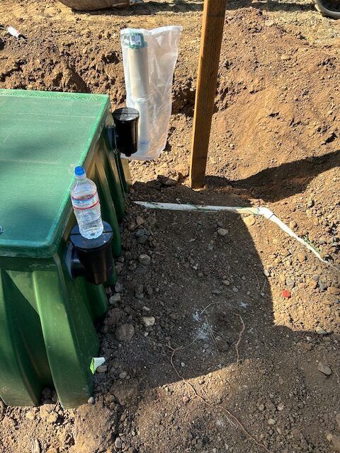 A bottle of water is sitting next to a green box in the dirt.