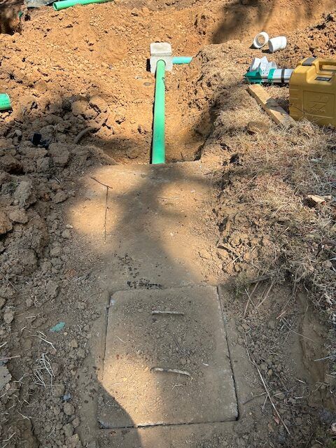 A green pipe is coming out of a hole in the ground.