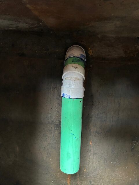 A green and white pipe is sitting on the floor in a room.