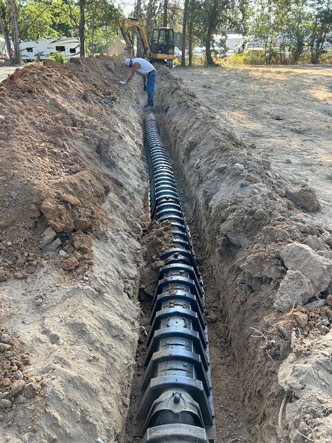 A man is working on a septic system in a trench.
