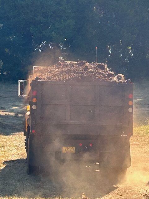 A dump truck is driving down a dirt road.