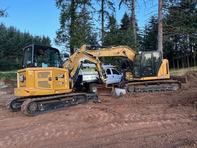 Two excavators are parked next to each other in a dirt field.