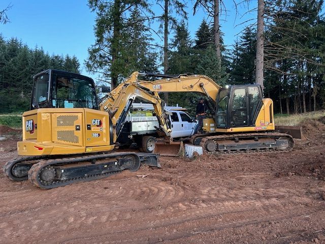 Two excavators are parked next to each other in a dirt field.