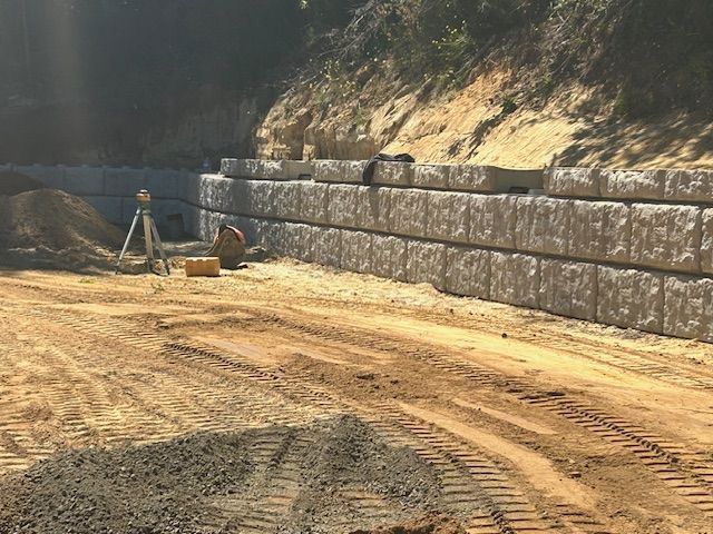 A large stone wall is being built on top of a dirt hill.