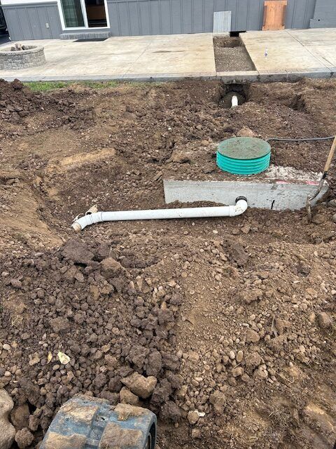 A septic tank is being installed in the dirt in front of a house.