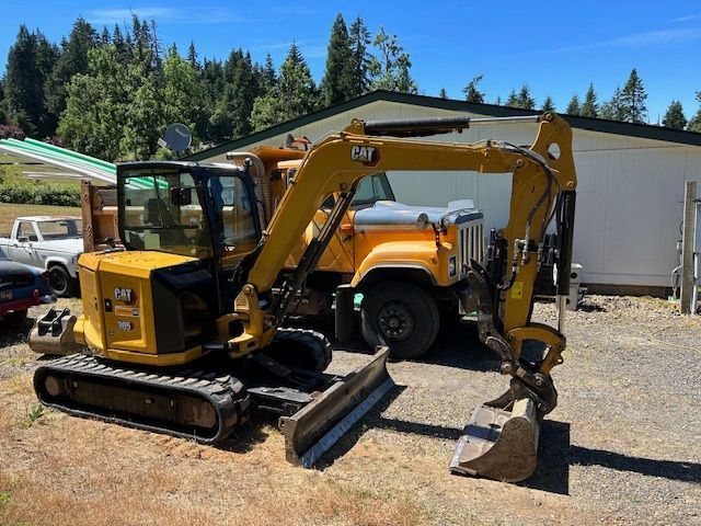 A yellow excavator is parked next to a yellow dump truck.