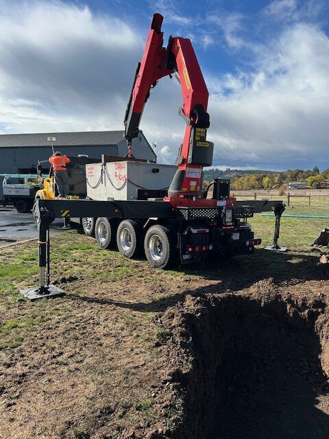 A large crane is sitting on top of a truck in a field.