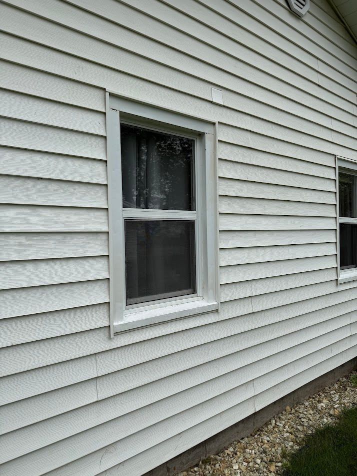 White siding with a window, white frame, and a glimpse of the interior. Another window is visible in the right side.