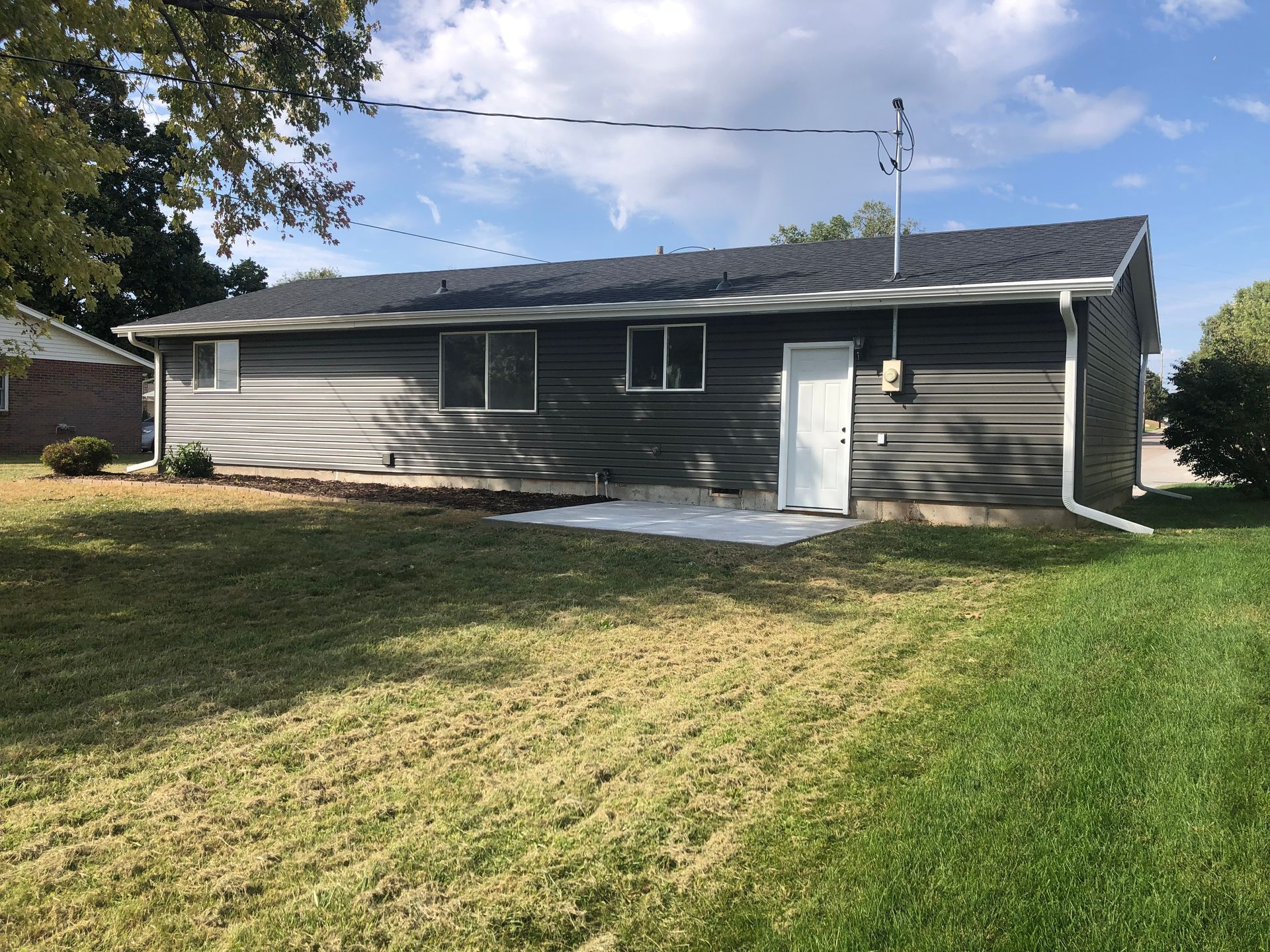 The back of a house with a large lawn in front of it.
