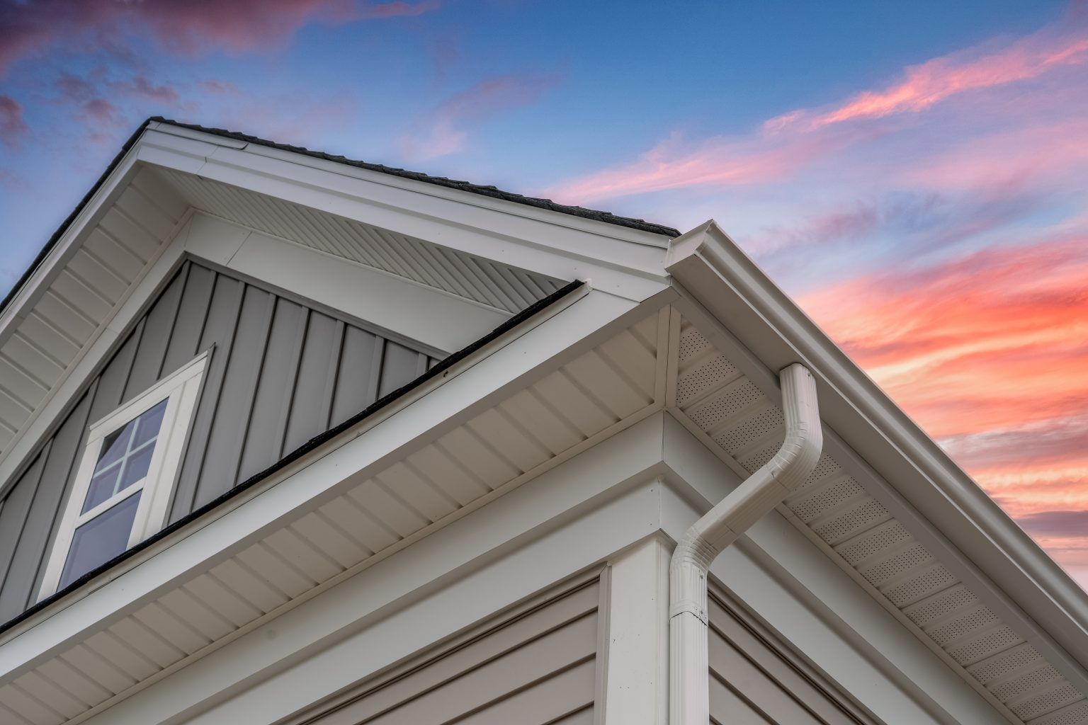 A close up of the roof of a house with a sunset in the background.