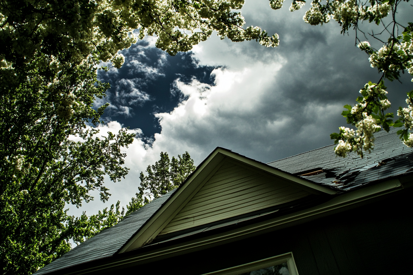 Looking up at the roof of a house with a cloudy sky in the background