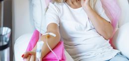 A woman is sitting in a hospital bed with an iv in her arm.