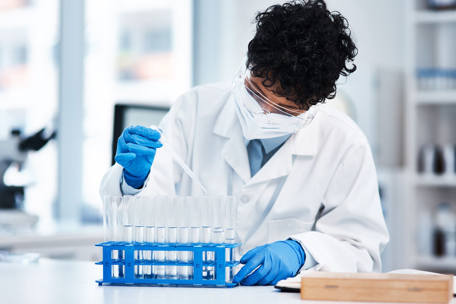 A scientist wearing a mask and gloves is working in a laboratory.