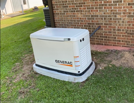 White Generac backup generator beside a brick house on grass