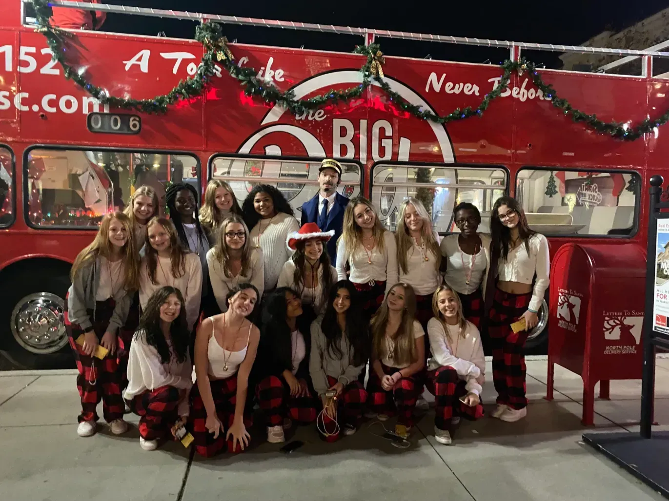 A group of people are posing for a picture in front of a red double decker bus.