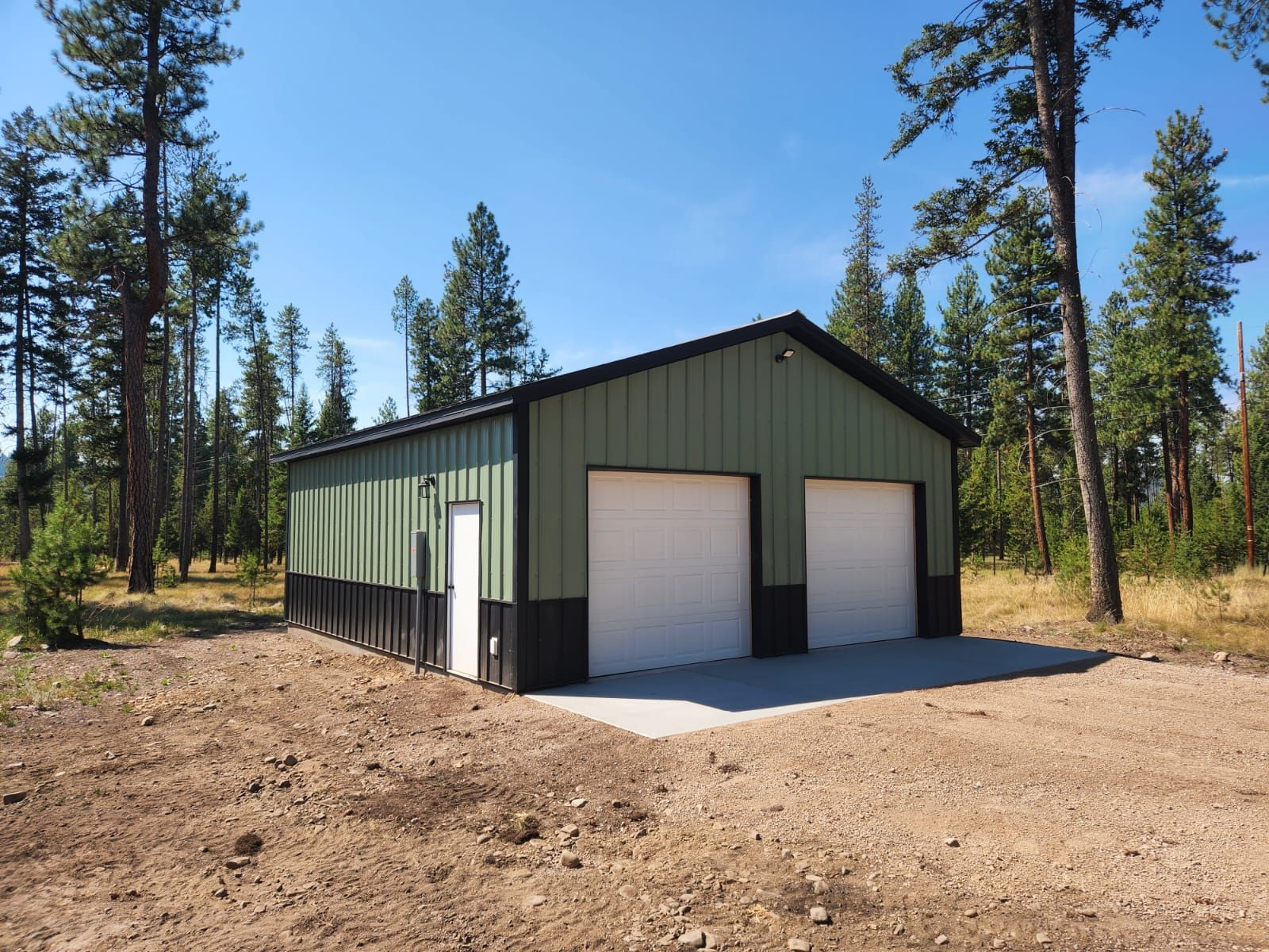 A green and black garage with two white garage doors