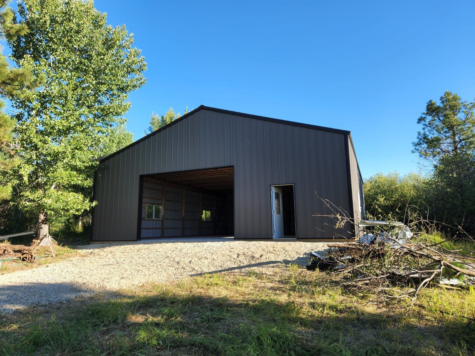 A large metal building with a garage door is sitting in the middle of a grassy field.