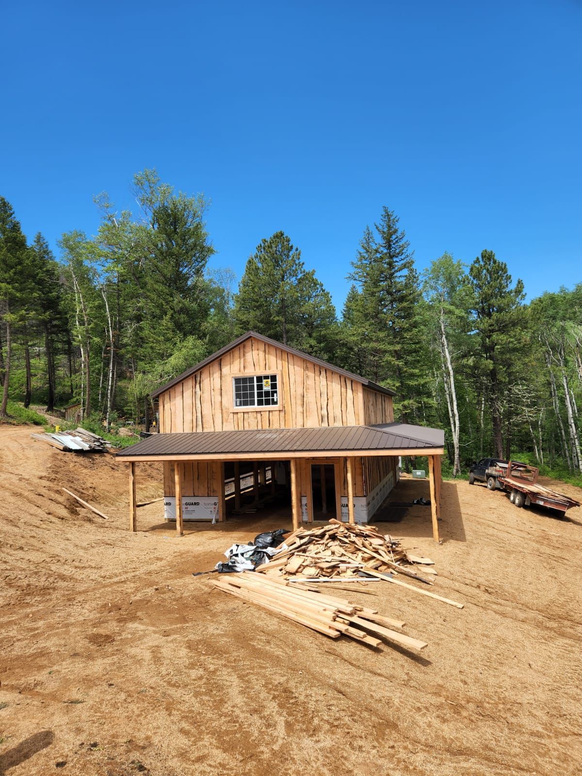 A large wooden barn is being built in the middle of a dirt field.