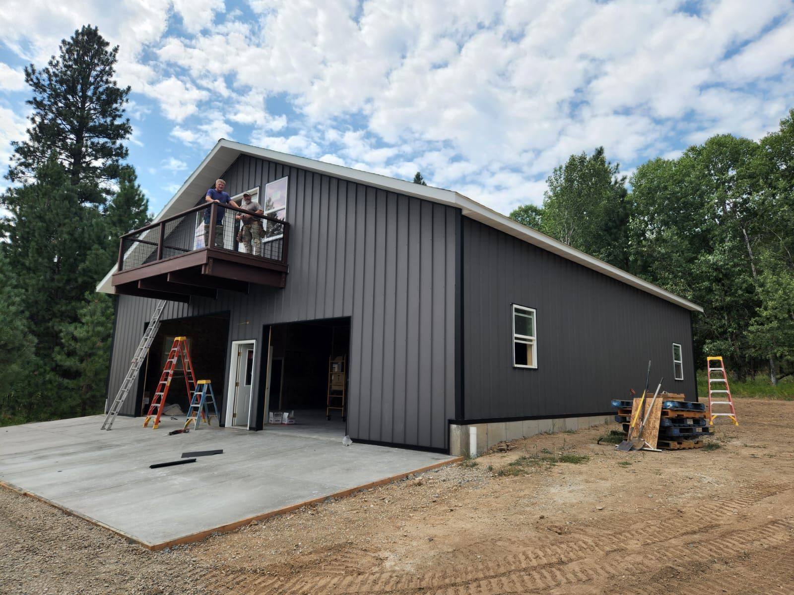 A man is standing on a balcony of a large metal building.