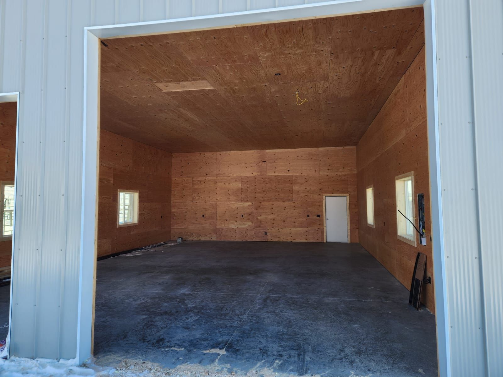 An empty garage with a concrete floor and wooden walls