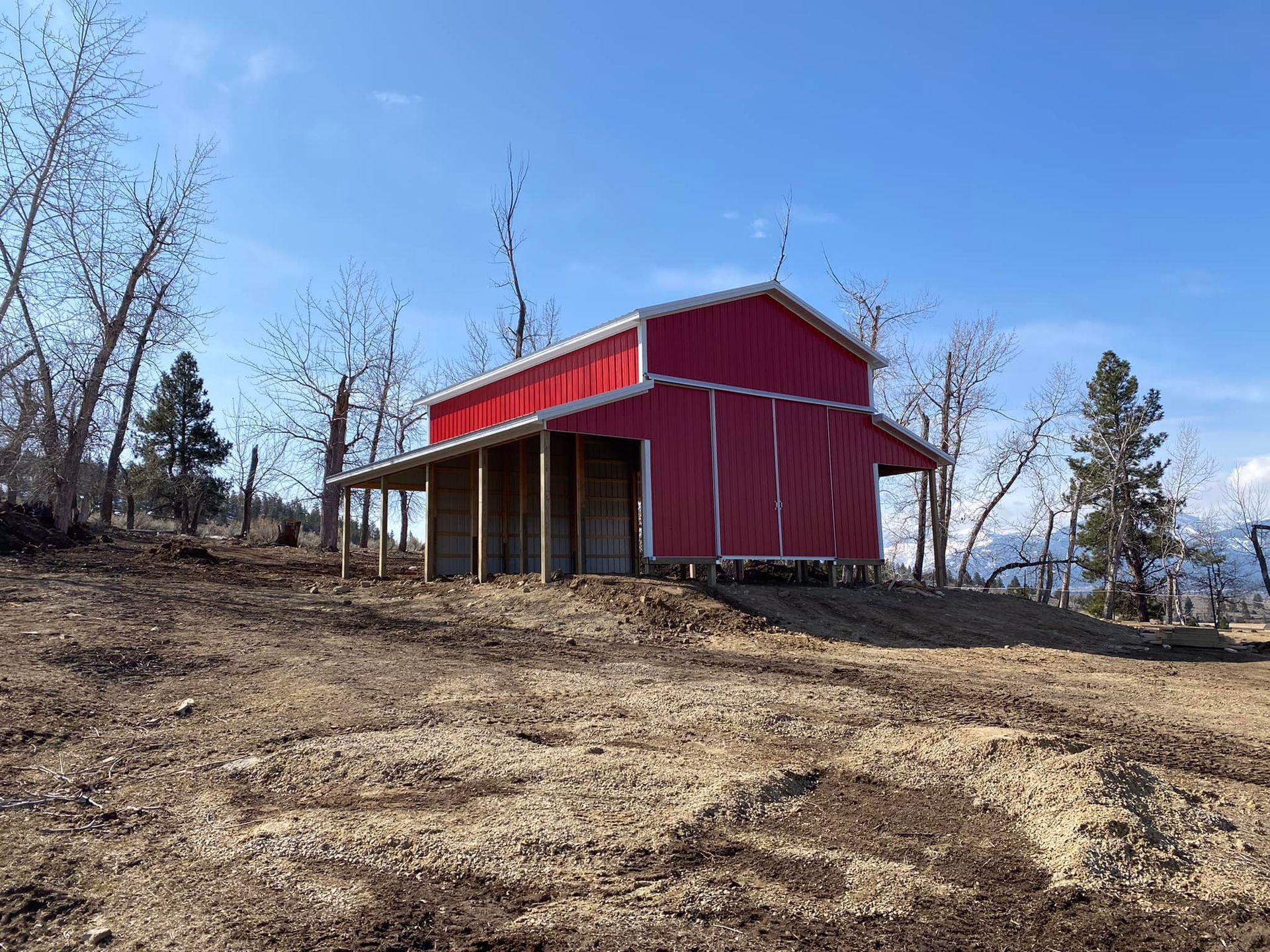 A red barn is sitting on top of a dirt hill.