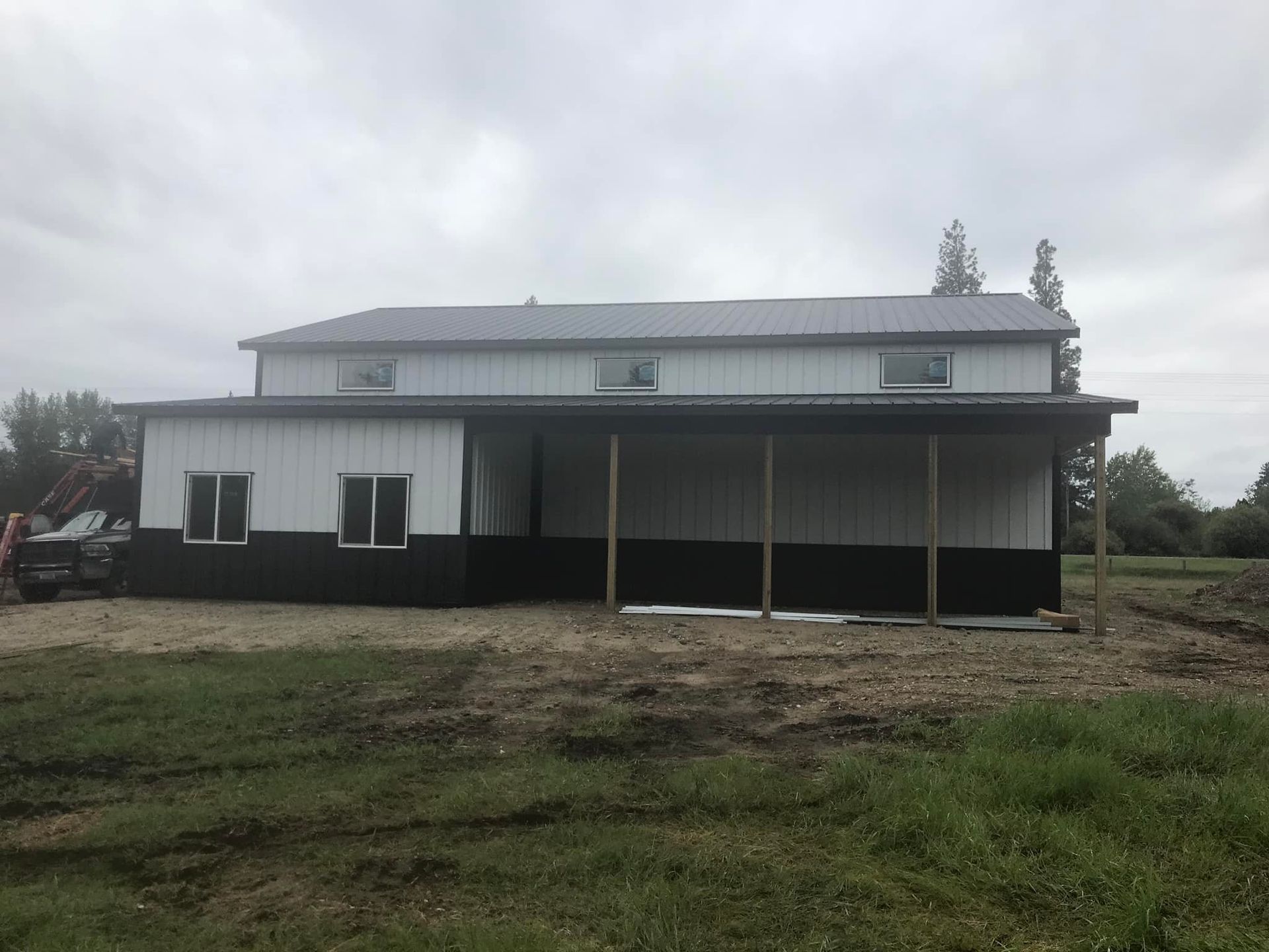 A large white and black building is sitting in the middle of a grassy field.