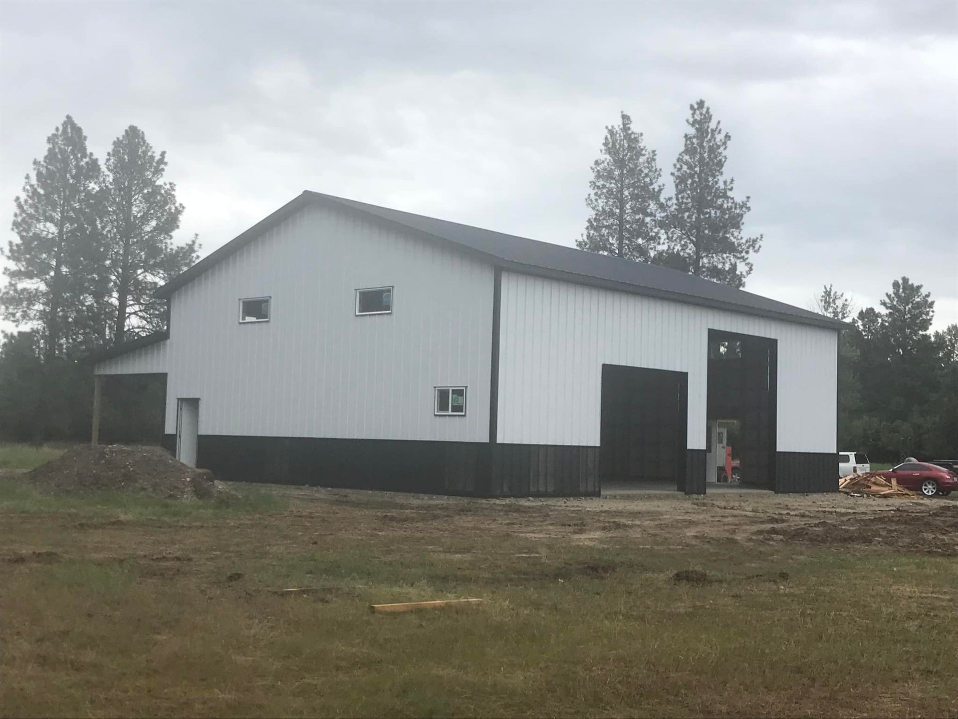 A large white and black building is sitting in the middle of a field.