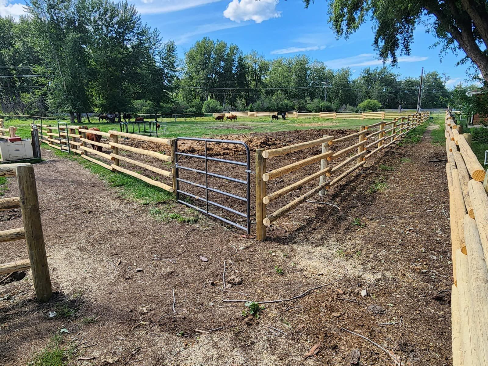 A wooden fence with a gate in the middle of a field.