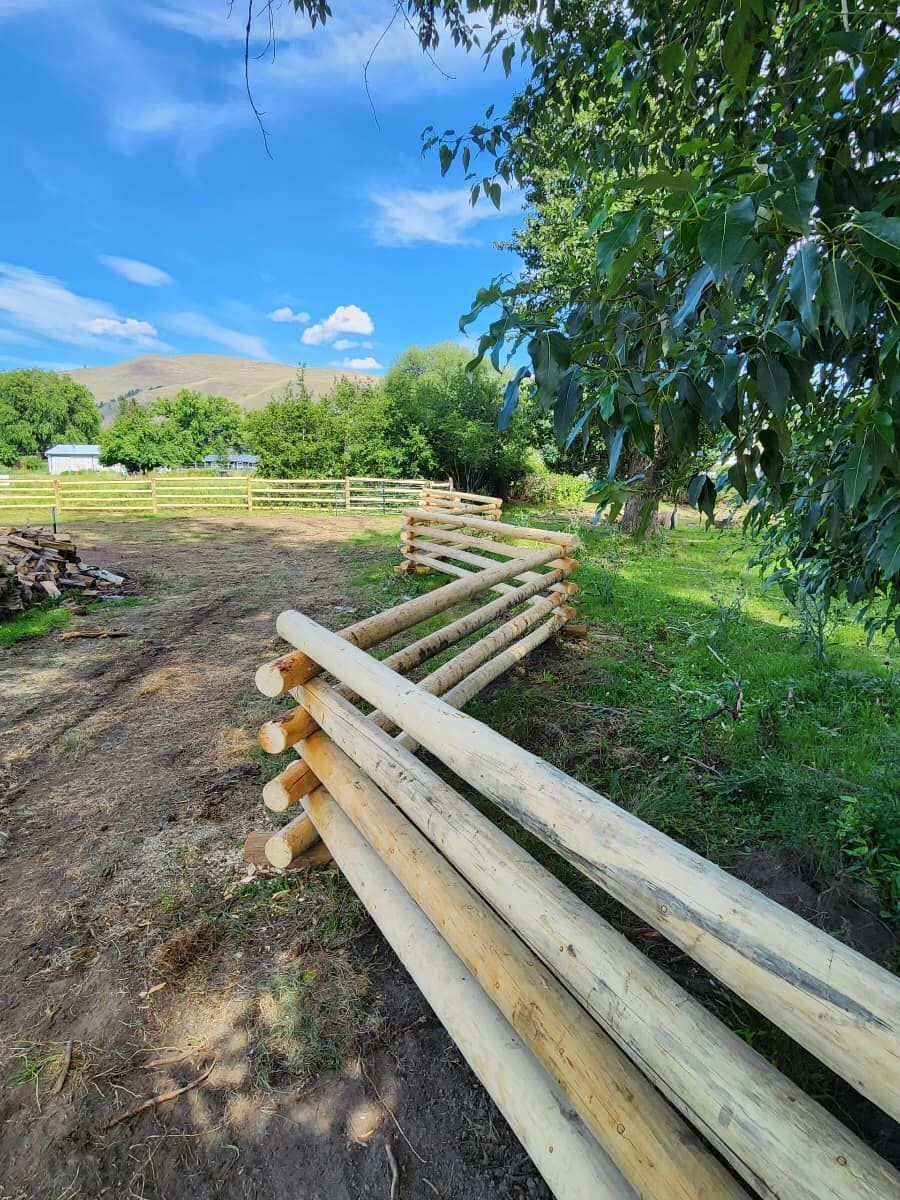 A pile of wooden poles sitting on top of a dirt road.