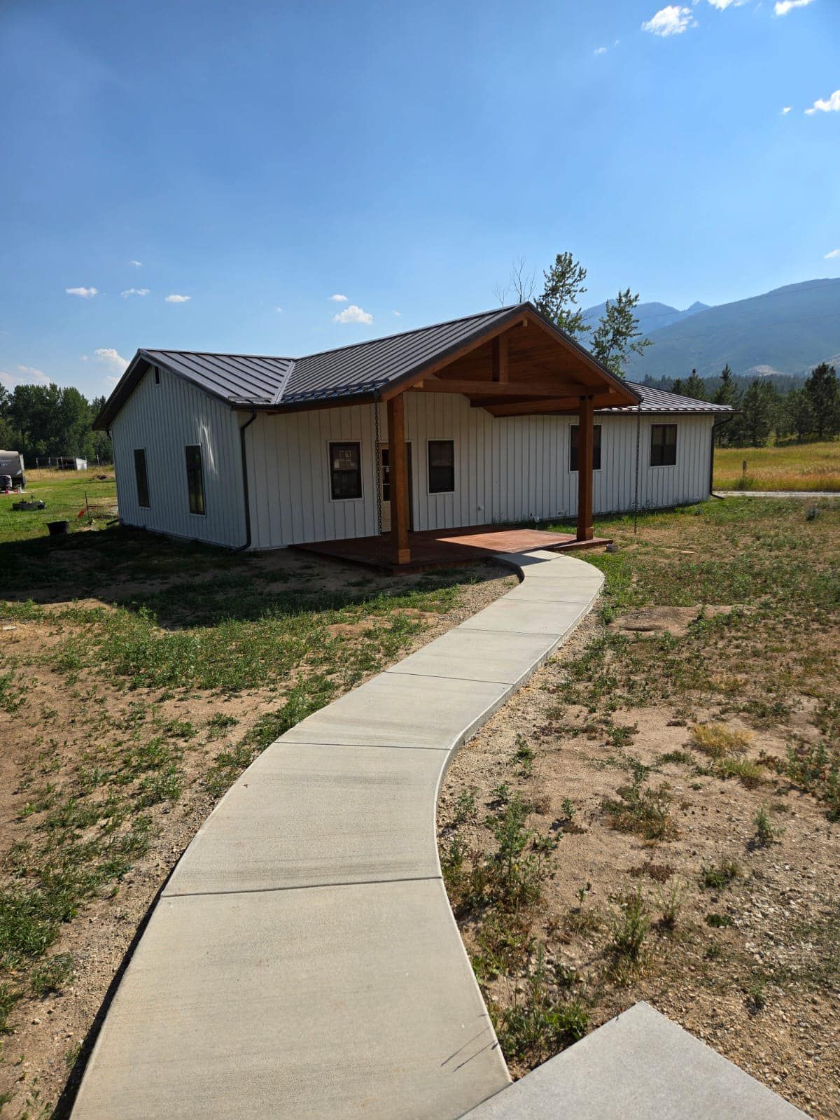 A concrete walkway leading to a white house with mountains in the background