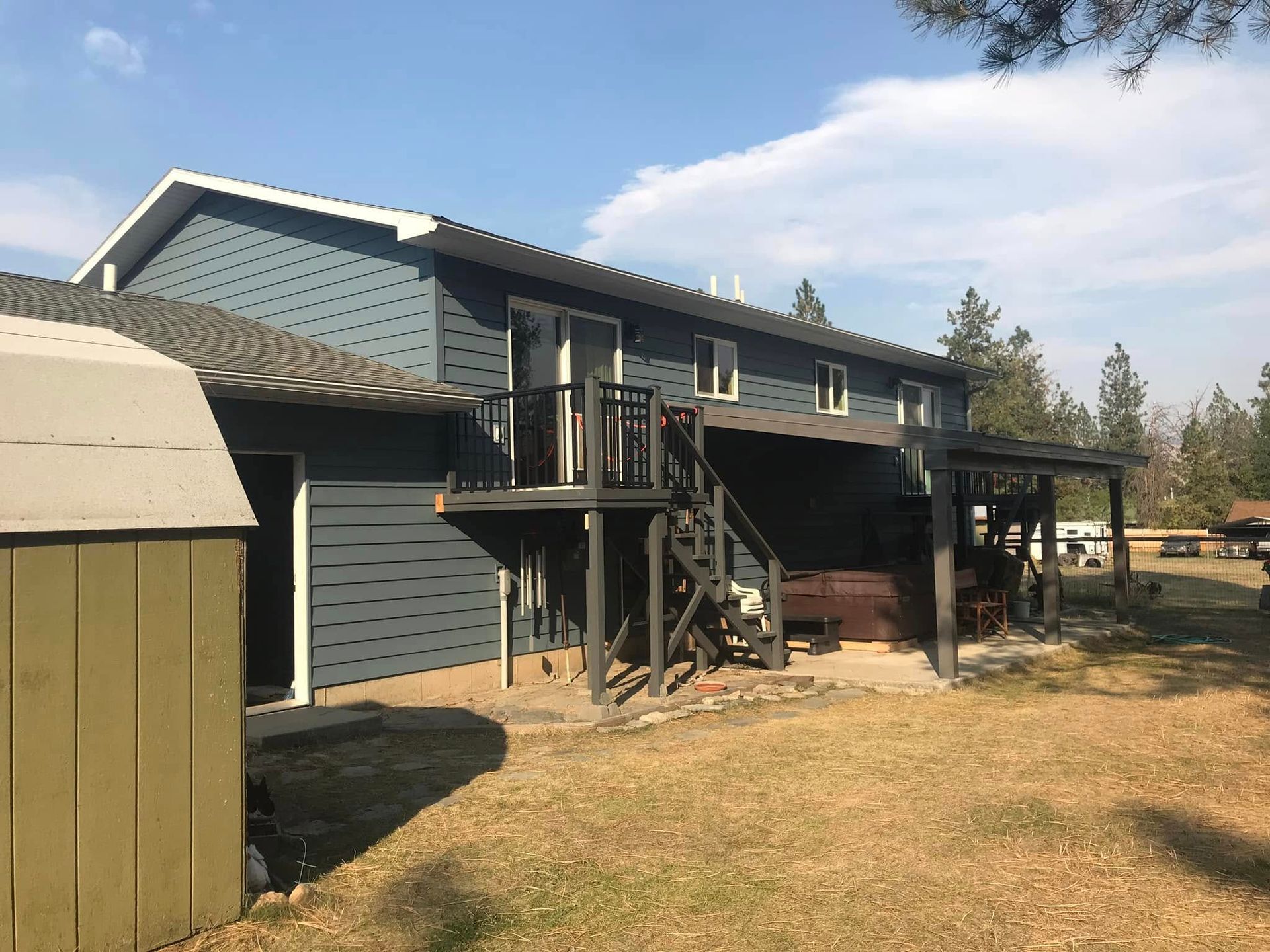 A large house with a green shed in front of it.