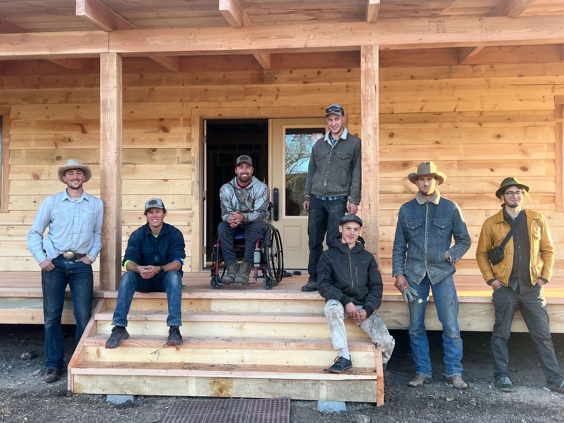 A group of men are standing on the porch of a wooden house.
