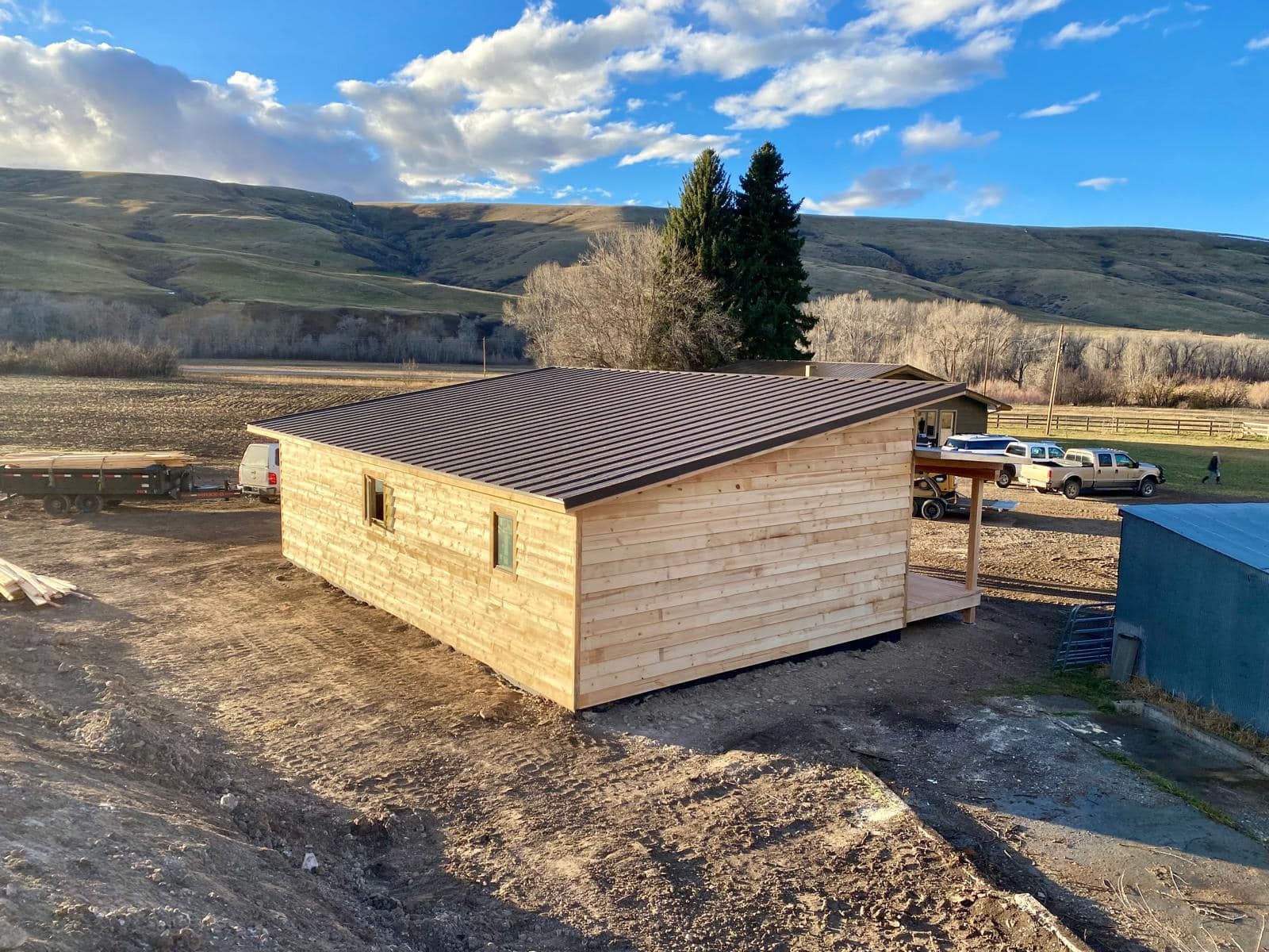 A small wooden house is sitting in the middle of a dirt field.