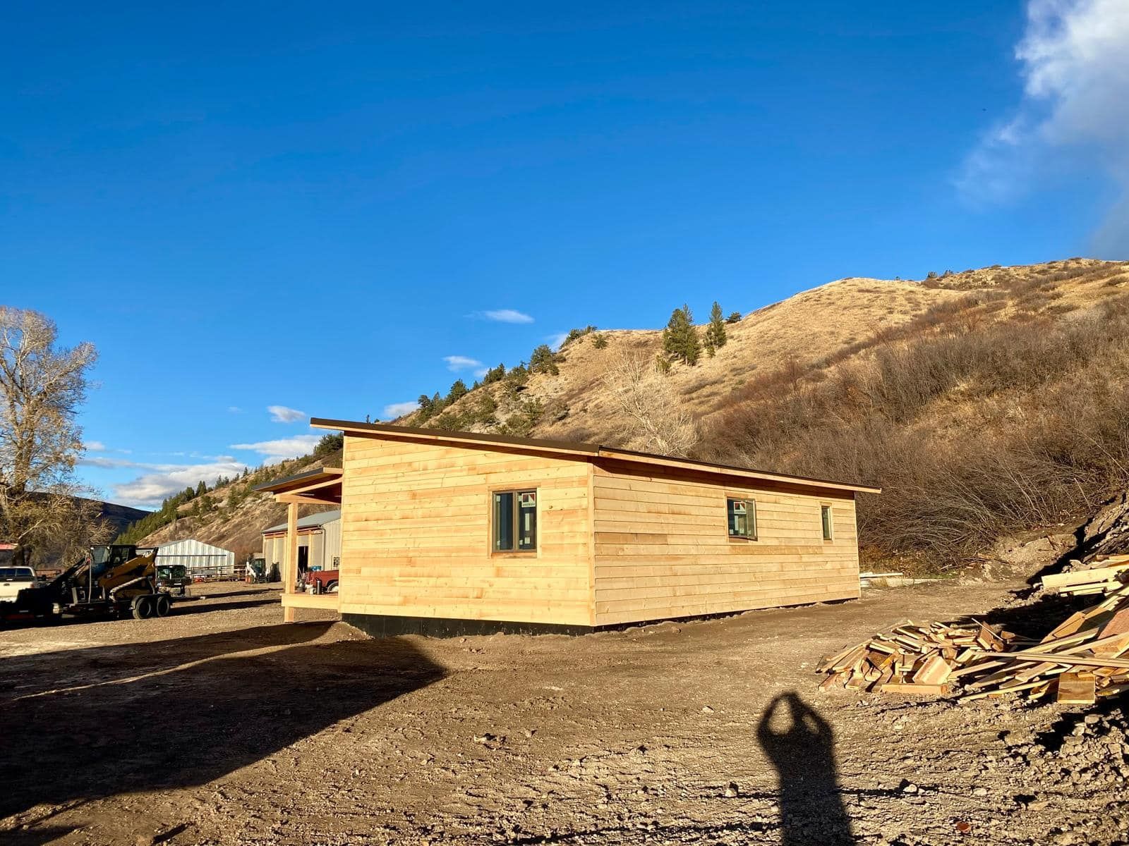 A wooden house is being built in the middle of a dirt field.
